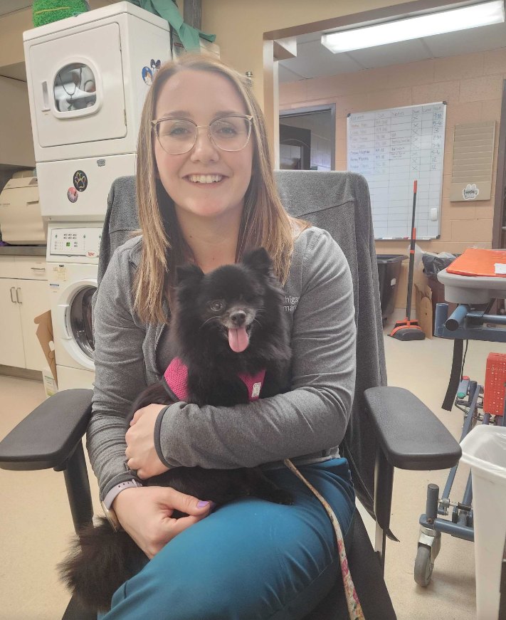 Vet tech sitting with a black Pomeranian in her lap
