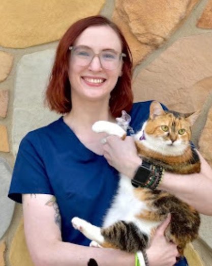 Vet tech with red hair holding a calico cat